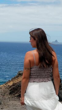 Woman enjoying ocean view from a cliff with arms outstretched