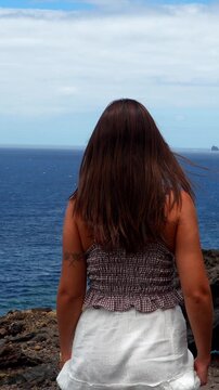 Happy young woman spreading arms wide open at the ocean