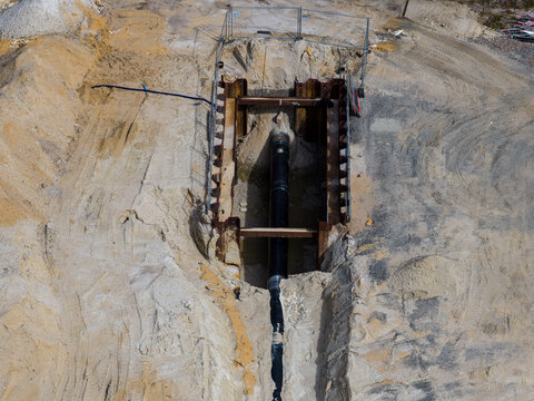 Aerial view of a large black pipeline being installed in a deep trench at the ZE PAK S.A. Elektrownia Patnow construction site in Konin, Wielkopolskie, Poland.
