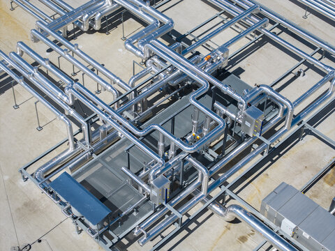 Aerial view of a complex network of industrial pipes and metal infrastructure on a rooftop in Poland.