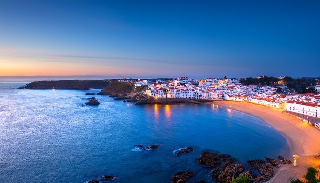 aerial view of ferragudo village with white houses red roofs and coastal beaches at blue hour dusk