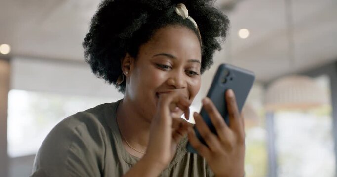 African American woman responding to message, tapping then holding blue phone in cafe in olive top