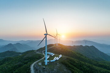 Renewable energy wind turbines installed on mountain ridges at sunrise, providing clean power. © tai