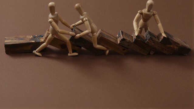 Three wooden figures push heavy, stacked logs in a line across brown surface.