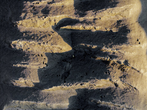 Aerial view of abstract sand patterns with deep shadows on a beach in Poland.