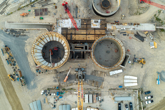 Aerial view of the American Fork wastewater treatment plant construction site with large circular concrete vats, water tanks, and heavy machinery in American Fork, Utah, United States.