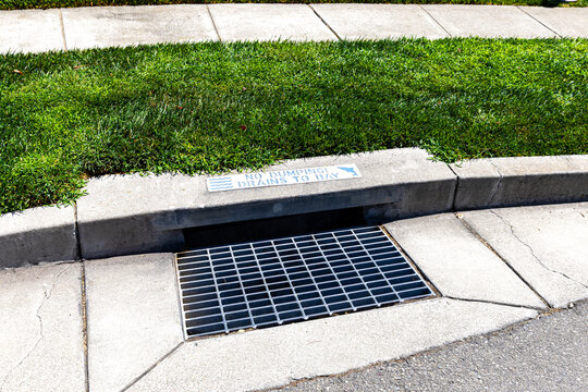 Stormwater drain along the edge of a roadway with a &ldquo;No Dumping, Drains to Bay&rdquo; sign, highlighting water pollution prevention, environmental protection, and watershed conservation.