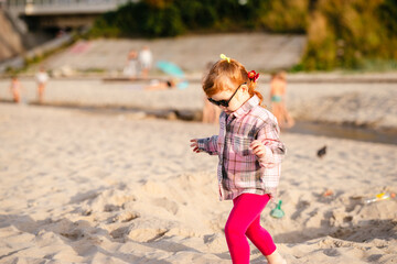 Fototapeta premium Child playing on the beach during sunset with sunglasses and a playful attitude