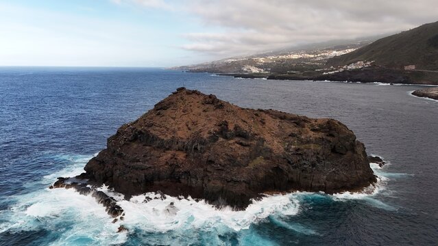 Aerial view of the volcanic rock formation known as Roque de Garachico surrounded by crashing waves in the Atlantic Ocean off the coast of Santa Cruz de Tenerife, Canary Islands, Spain.