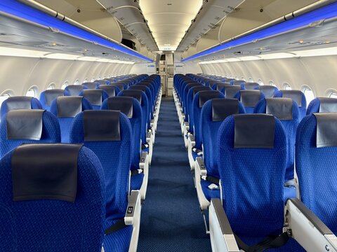 Empty rows of blue seats in the passenger cabin interior of an airplane in Japan
