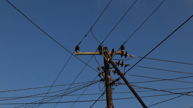 Network of electric cables on electric poles with a clear blue sky in the afternoon