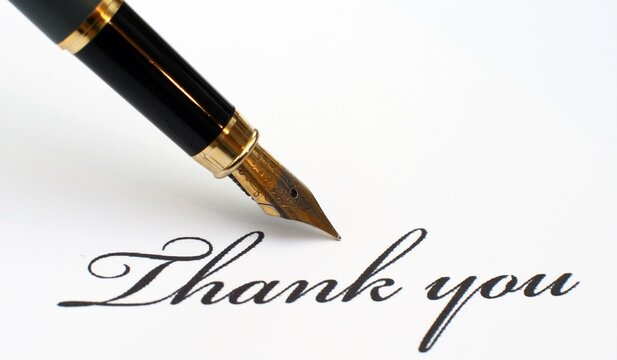 Fountain pen writing thank you in calligraphy on white paper with calligraphy