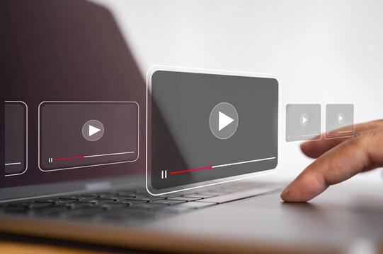 Digital video streaming interface with play buttons over laptop as user interacts with online media, representing video content, multimedia technology, entertainment and online playback.