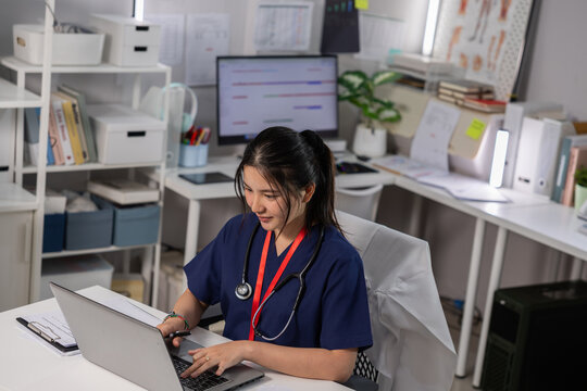 Nurse laptop office clinic desk stethoscope healthcare medical computer uniform focused worker typing at workspace with paperwork and shelf in bright professional room