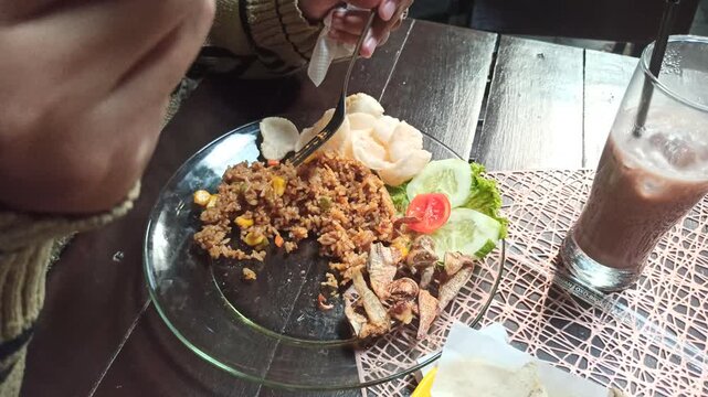 A plate of classic Indonesian fried rice served with crispy salted fish, showcasing a simple and traditional home-style meal with authentic Indonesian flavors.