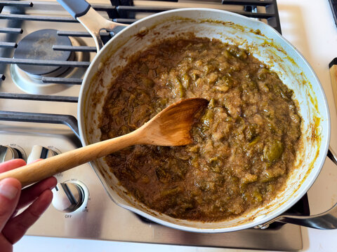 cooking freshly harvested sliced figs in deep pan on top of stove for producing homemade jam which is being caramelized