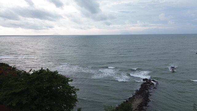 Scenic drone flight over Anyer Beach featuring gentle waves and a tropical shoreline in Banten, Indonesia.