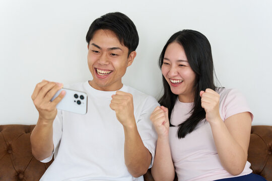 Young Japanese Man and Woman Excitedly Watching Sports on Smartphone Together