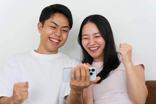 Young Japanese Man and Woman Excitedly Watching Sports on Smartphone Together