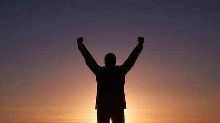 Fototapeta premium Silhouette of a person raising arms in triumph against a vibrant sunset sky