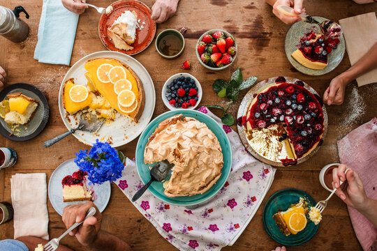 Top view of a table with various desserts and fruits being shared.