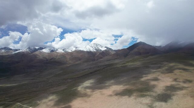 Drone view landscape of snow capped mountains with moving clouds and shadows on land in Ali, Tibet, China, 4k real time footage b roll shot travel concept.