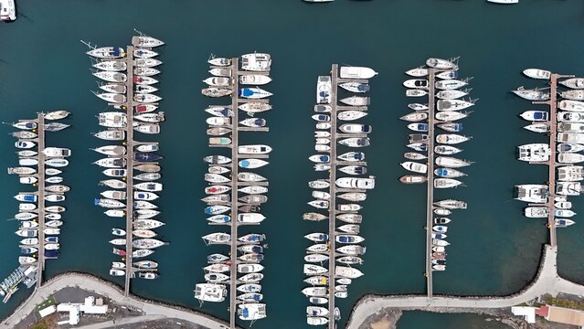 Aerial view of Tenerife marina featuring rows of docked sailboats and yachts in the deep blue water of Santa Cruz de Tenerife, Canary Islands, Spain.