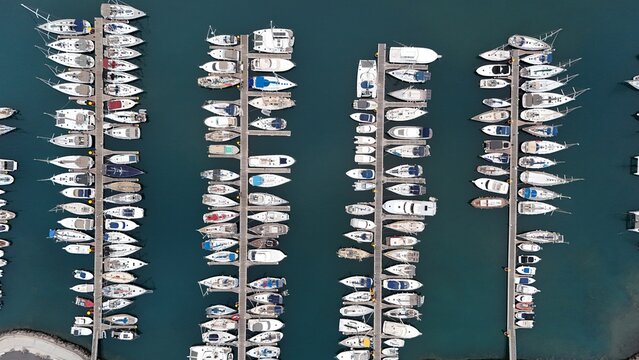 Aerial view of Tenerife marina featuring rows of docked sailboats and yachts in the clear blue water of Santa Cruz de Tenerife, Canary Islands, Spain.