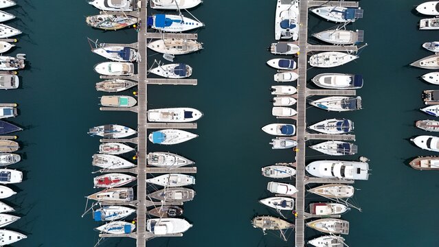 Aerial view of Tenerife marina with numerous yachts docked in rows along wooden piers in the deep blue water of Santa Cruz de Tenerife, Canary Islands, Spain.