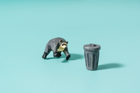 Jimothy Raccoon and trash can hand carved from wood. Studio shot.