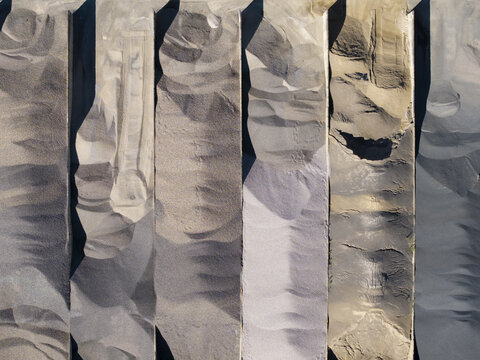 Aerial view of aggregate storage bins at Masfalt Sp. z o.o. WMB, showing various textures of sand and gravel in industrial compartments in Dabrowa Gornicza, Wojewodztwo slaskie, Poland.