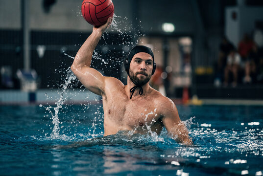 Male water polo player holding a red ball ready to throw in a swimming pool