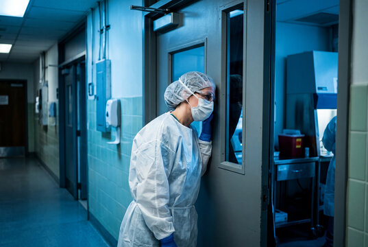 Exhausted Healthcare Worker in PPE Leaning Against Laboratory Door