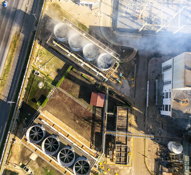 Aerial view of a thermoelectric power plant with large cooling towers emitting steam, industrial infrastructure, and surrounding grounds in Merida, Yucatan, Mexico.