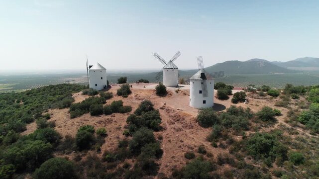 Traditional windmills dotting a dry landscape under a clear blue sky in rural spain