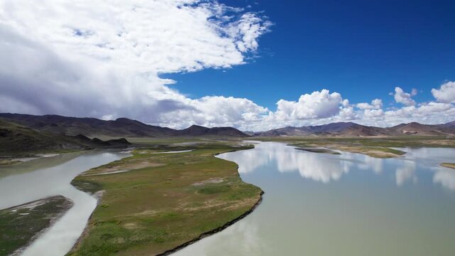Drone view landscape of mountains and wetland rivers and lakes with blue sky and white clouds background and reflections in sunny day in Tibet, China, 4k real time footage b roll travel concept.
