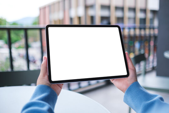 Mockup image of a woman holding digital tablet with blank white desktop screen in cafe