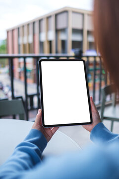 Vertical mockup image of a woman holding digital tablet with blank white desktop screen in cafe