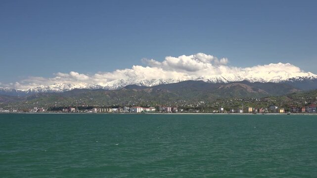 Rize Turkey Black Sea coastal city stands below snowy Pontic mountains and cloudy sky.