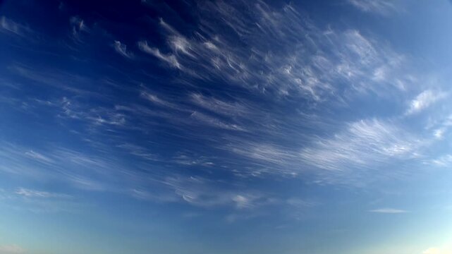 Cirrus clouds drift across blue sky in timelapse, showing cirrus fibratus streaks.