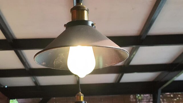 A vintage industrial pendant lamp featuring a dark metal dish-shaped shade and a warm LED filament bulb, creating a cozy retro ambiance for caf&eacute;s, restaurants, and interior spaces.