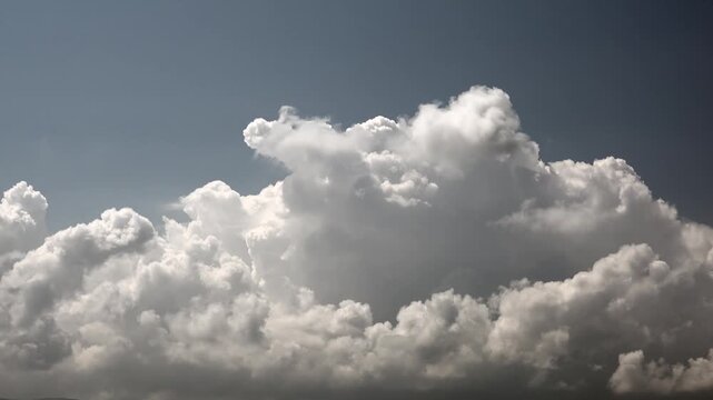 Time lapse fluffy clouds drifting across bright blue daytime sky in humid weather.