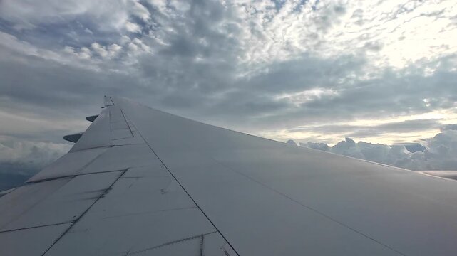 The wing of a large passenger plane floating in the sky during the rainy season.
