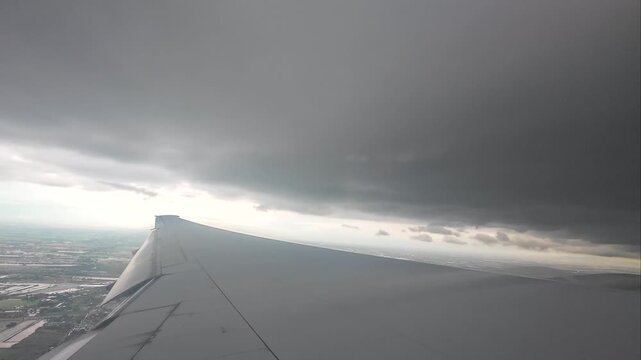 The wing of a large passenger plane floating in the sky during the rainy season.