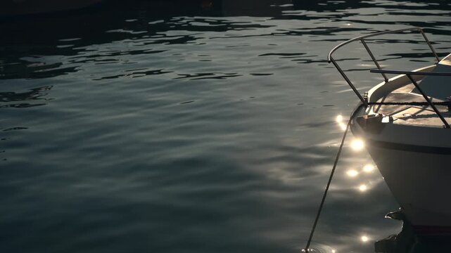 Quiet morning scene in a marina with sun flare reflecting on sea water around a boat hull. Concept of nautical travel, maritime leisure, and coastal tranquility. 4K.