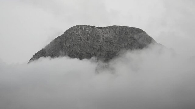Peaceful mountain peak rises above the clouds in Spain in a calm atmospheric time lapse.