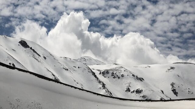 Timelapse warm clouds drifting above snow covered mountain ridges in spring in Antarctica.