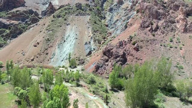 Exposed mineral outcrop reveals red strata and ore bearing layers across a barren slope.
