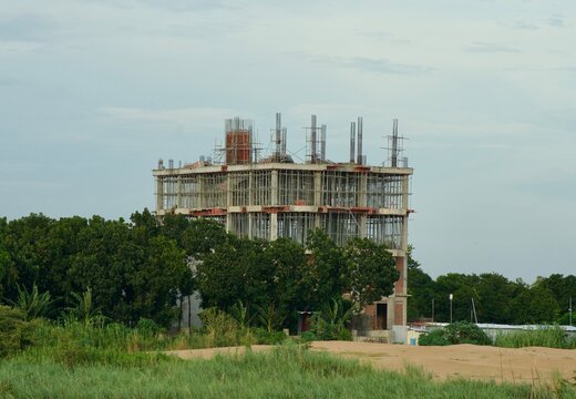 Multi-Story Concrete Building Under Construction Surrounded by Trees