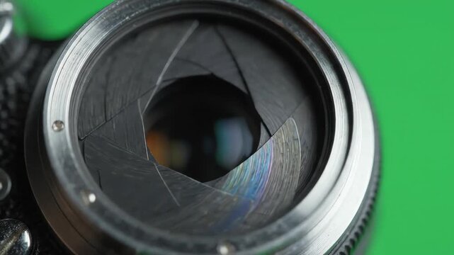 Professional camera shutter aperture mechanism closing and opening rapidly on a green screen chroma key background for video transitions